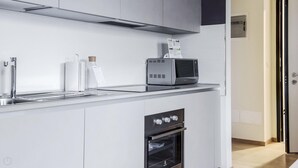 Una cocina moderna con horno empotrado, microondas y pileta de acero inoxidable.