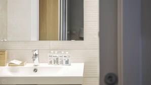 Un baño con un lavabo blanco, un espejo y artículos de aseo.