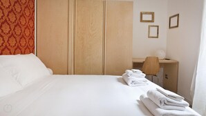 Hotellihuoneessa on sänky, työpöytä ja tuoli. Sängyllä on pyyhkeitä.