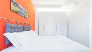 A modern bedroom with a white bed, grey headboard, and orange walls. - Italianway Easy - Ciaia 6 B (Milan)