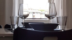 A dining table with two wine glasses and a bowl, set against a window with a view of buildings. - Italianway Easy - Corso Lodi 78 (Milan)