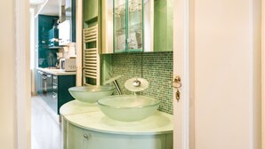 A bathroom with a green tiled backsplash, a white sink with two bowls, and a glass cabinet above the sink. - Mi-clod9a3 - Corso Lodi 9 (Milan)