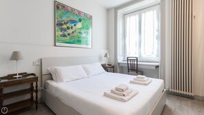 A hotel room with a large bed, two bedside tables, a window with curtains, and a painting on the wall. - Mi-clod9a3 - Corso Lodi 9 (Milan)