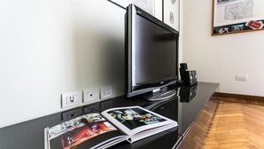 A modern hotel room with a flat-screen TV, a magazine on the console table, and a wooden parquet floor. - Italianway Easy - Da Procida 25 (Milan)