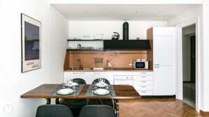 A compact kitchen with a dining area, a microwave, a kettle, and a refrigerator. - Italianway Easy - Da Procida 25 (Milan)