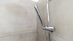 Un angolo di un bagno con doccetta e maniglia in cromo.