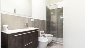 Ein modernes Badezimmer mit einem Holzkosmetikschrank, einer Duschkabine aus Glas und einer Toilette.