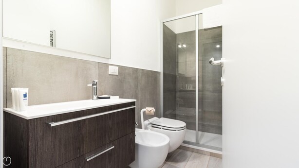 A modern bathroom with a wooden vanity, a glass shower enclosure, and a toilet. - Italianway Easy - De Cristoforis 5 (Milan)