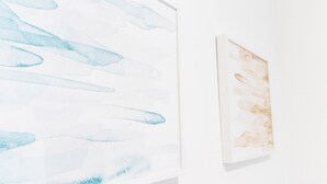 Eine Wand mit zwei Kunstwerken; eines abstrakt mit blauen Formen, das andere in Brauntönen.