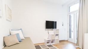 A minimalist living room with a sofa, a flat-screen TV, and a white storage unit. - Italianway Easy - De Cristoforis 5 (Milan)