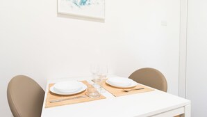 A clean, white dining table set with two plates, two glasses, a knife, and a spoon on a bamboo placemat. - Italianway Easy - De Cristoforis 5 (Milan)