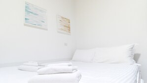 A clean, white hotel room with a neatly made bed, two wall-mounted artworks, and a small bedside table with a lamp. - Italianway Easy - De Cristoforis 5 (Milan)