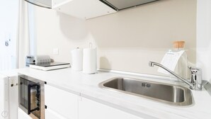 Eine moderne Küche mit eingebautem Geschirrspüler, einer Edelstahl-Spüle und einer Küchenpapierrolle auf der Arbeitsfläche.