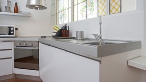 A modern kitchen with white cabinetry, a built-in oven, a microwave, a stainless steel sink, and a window with stained glass. - Italianway Easy - Dogana 3 (Milan)