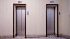 Two closed elevator doors in a hallway with tiled flooring and a textured wall. - Italianway Easy - Dogana 3 (Milan)