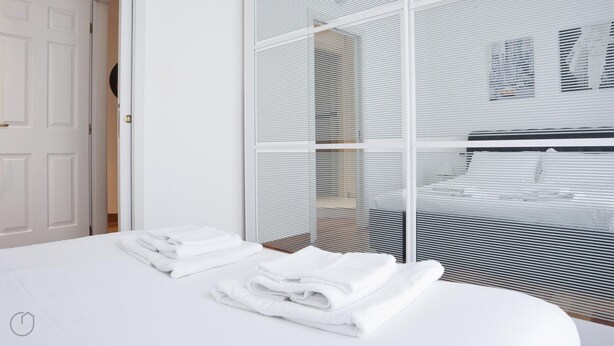A modern bedroom with a neatly made bed, a white door, and a large window with blinds. - Italianway Easy - Dogana 3 (Milan)