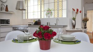 A modern kitchen with a dining table set for two, featuring a vase of red roses, two wine glasses, and a bowl. - Italianway Easy - Dogana 3 (Milan)