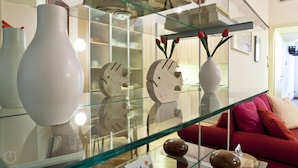 A modern living room with a glass coffee table, white vases, and decorative clocks. - Italianway Easy - Fiori Chiari 20 (Milan)