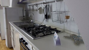 A compact kitchen with a gas stove, stainless steel appliances, and a hanging pot rack. - Italianway Easy - Forcella 11 (Milan)