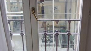 A view through a window with a white door, a balcony with metal railings, and a table with a teapot and cup. - Italianway Easy - Forcella 11 (Milan)