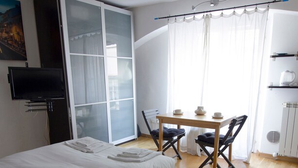 A bedroom with a bed, a desk with chairs, a television, and a window with curtains. - Italianway Easy - Forcella 11 (Milan)
