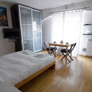 A bedroom with a bed, a desk with chairs, a television, and a window with curtains. - Italianway Easy - Forcella 11 (Milan)