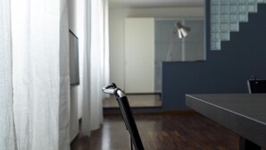 Un pasillo con una mesa de comedor, sillas, una escalera y un espejo en la pared.