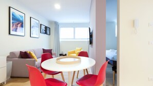 Ein modernes Hotelzimmer mit einer Couch, roten Stühlen, einem runden Tisch und einem Bett.