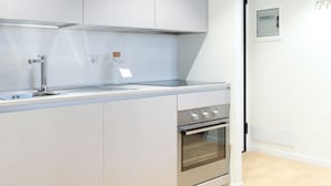 Eine moderne Küche mit weißen Schränken, Edelstahlgeräten und einem eingebauten Backofen.