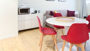 Eine moderne Küche mit Mikrowelle, einem Esstisch mit roten Stühlen und einem hundszahn-Muster Sofa.