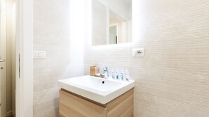 A modern bathroom with a white sink, wooden cabinetry, and a mirror above it.