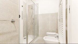 Een moderne badkamer met een glazen douchecabine, toilet en bad.