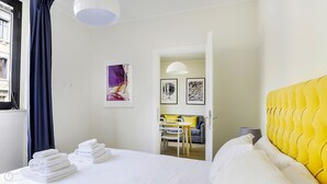 Een hotelkamer met een bed, een tafel met stoelen en een deur naar een andere kamer.