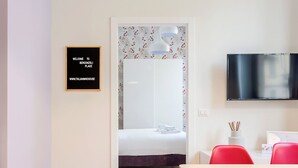 Une chambre d’hôtel équipée d’un lit, d’une télévision, d’un bureau avec une chaise et d’une pancarte de bienvenue encadrée.