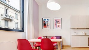 Une pièce moderne comprenant une table à manger, des chaises rouges, un canapé et un coin cuisine.