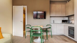 A compact kitchen with a dining area, featuring a microwave, oven, and a flat-screen TV on the wall. - Mi-brgz1c4 Bergonzoli Place - Bilo B - Canoe (Milan)