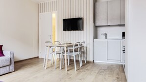 A compact living space with a dining area, kitchenette, and a TV mounted on the wall. - Mi-brgz1c3 Bergonzoli Place - Bilo B - Hugo (Milan)