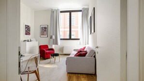 A modern living room with a red chair, a patterned sofa, and a dining area with a table and chairs. - Mi-brgz1c1 Bergonzoli Place - Bilo B - Nina (Milan)