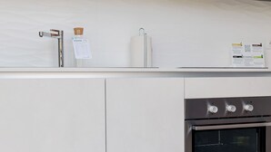 Cozinha moderna com eletrodomésticos de aço inoxidável, forno embutido e coifa de aço inoxidável.