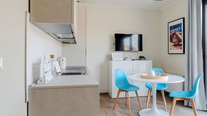 A modern kitchen with a built-in stove, a sink, and a dining area with a round table and blue chairs. - Mi-brgz1b4 Bergonzoli Place - Terrace B - On the Grass (Milan)