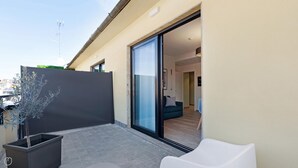A modern apartment with a sliding glass door leading to a living area, a potted plant, and a white chair. - Mi-brgz1b4 Bergonzoli Place - Terrace B - On the Grass (Milan)