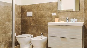 A bathroom with a toilet, bidet, and a sink with a mirror above. - Mi-brgz1b3 Bergonzoli Place - Trilo - Shakespeare (Milan)