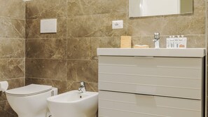 A modern bathroom with a toilet, bidet, and a vanity with a mirror. - Mi-brgz1b3 Bergonzoli Place - Trilo - Shakespeare (Milan)