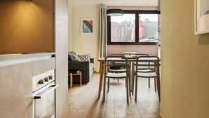 A compact kitchen with a dining area, a sofa, and a window with a view of buildings. - Mi-brgz1b3 Bergonzoli Place - Trilo - Shakespeare (Milan)