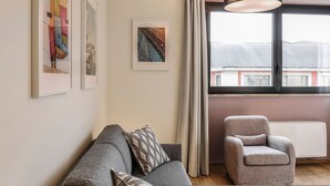 A living room with a sofa, a chair, and a window with a view of buildings. - Mi-brgz1b3 Bergonzoli Place - Trilo - Shakespeare (Milan)