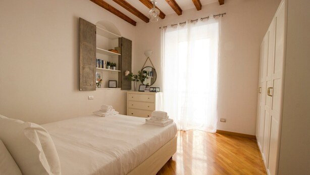 Quarto com cama, cômoda, espelho e janela com cortinas.