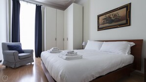 A hotel room with a large bed, a chair, a wardrobe, and a painting on the wall. - Italianway Comfort - Lombardia 96 (Milan)