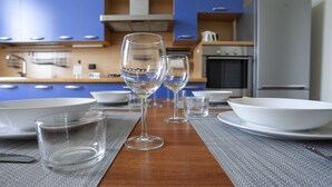 A modern kitchen with blue cabinets, a wooden table set with wine glasses and plates, and a stainless steel oven. - Italianway Comfort - Lombardia 96 (Milan)