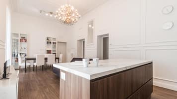 Una cocina moderna con una isla grande, armarios blancos y una araña.