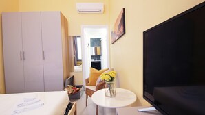 Een knus hotelkamer met een bed, een televisie, een tafeltje met een bloemenvaas, een stoel en een kledingkast.